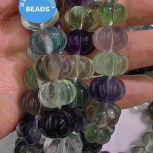 Puede incluir: Una hebra de cuentas de fluorita facetadas de color verde, morado y transparente. Las cuentas están talladas en forma de calabaza. Las cuentas están enhebradas en un hilo blanco. Las cuentas tienen un diámetro aproximado de 2,5 cm. WK DIY Jewelry Beads.