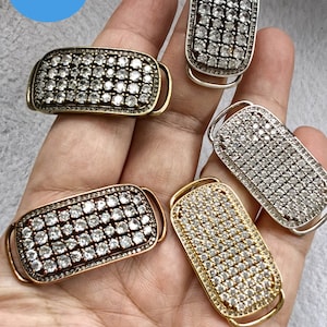 May include: Four different metal rectangular clasps with clear rhinestones. The clasps are in silver, gold, and two shades of bronze.
