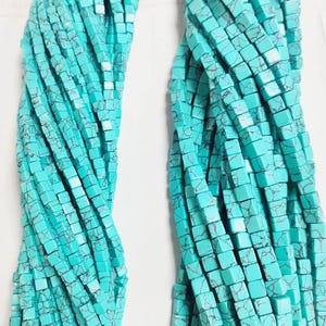 Peut inclure: Un brin de perles carrées bleu turquoise avec un motif marbré blanc. Les perles sont enfilées sur une longue chaîne et sont parfaites pour la fabrication de bijoux.