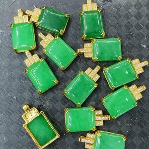 May include: A collection of jade pendants, each featuring a rectangular green jade stone set in a gold-colored frame. The pendants have a design resembling a cigarette pack, with small, sparkling accents.