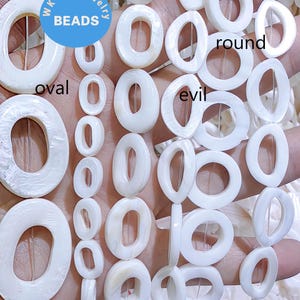 May include: White mother of pearl beads in round and oval shapes. The beads are strung on a clear thread. The text "WK DIY Jewelry Beads" is visible on a blue label. The text "round" and "oval" are visible on the image.