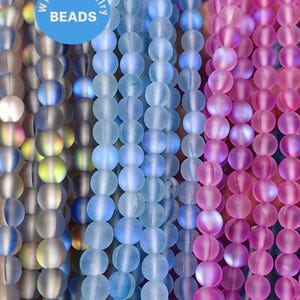 May include: Assortment of iridescent glass beads in shades of blue and pink. The beads are round and have a frosted finish. The beads are strung on a string and are ready to be used for jewellery making.