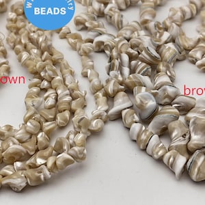 May include: A strand of white and brown shell beads with a brown matrix. The beads are irregular in shape and have a natural, organic look.