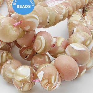 May include: A strand of pink and white shell beads with a swirl pattern. The beads are approximately 1 inch in diameter.