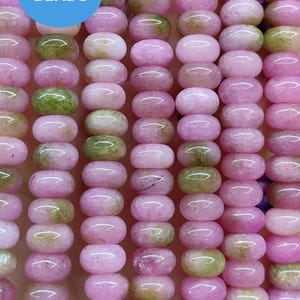 Pode incluir: Fios de contas ovais rosa e verdes. As contas são uma mistura de rosa sólido e rosa com inclusões verdes e castanhas. A imagem inclui o texto "WK DIY Jewelry BEADS" num círculo azul.
