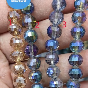 Può includere: Tre fili di perline di vetro sfaccettate. Le perline sono iridescenti e sono disponibili in tre colori: oro, blu e viola. Le perline sono infilate su uno spago trasparente. L'immagine include il testo "WK DIY Jewelry Beads".