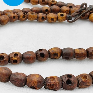 May include: A brown wooden necklace with skull-shaped beads. The necklace is made from natural wood and has a rustic look.