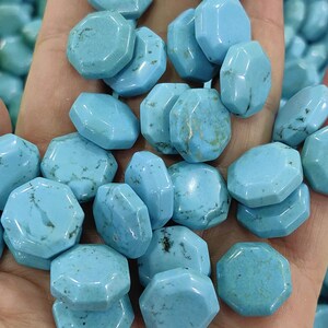 May include: A collection of light blue, faceted gemstone beads. The beads have an irregular, octagonal shape and a polished surface. The color is a vibrant turquoise, with some beads showing natural variations in color and veining. These beads are suitable for jewelry making.