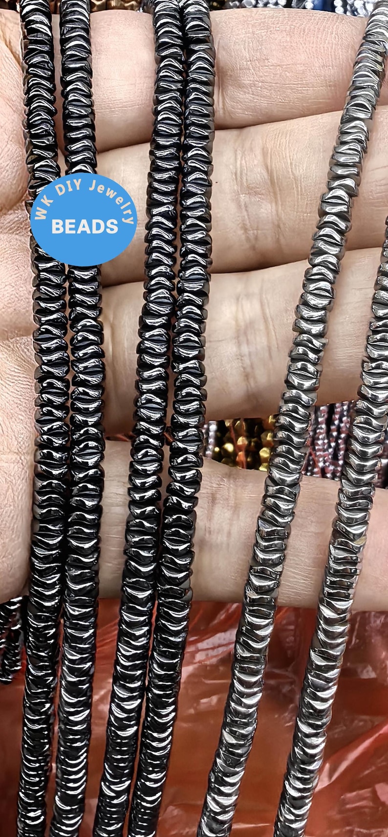May include: A close-up of four strands of black hematite beads. The beads are faceted and have a shiny finish. The beads are strung on a clear elastic cord. The beads are approximately 6mm in diameter.  WK DIY Jewelry Beads.