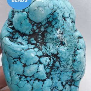 Peut inclure: Grosse pierre turquoise de forme irrégulière, veinée de noir. La pierre présente une surface lisse et polie, d'un bleu-vert vif. Un cercle bleu avec le texte "WK DIY Jewelry BEADS" est visible.