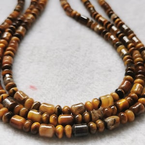 May include: A multi-strand necklace made of brown and gold tiger's eye beads.