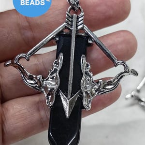 May include: Silver tone pendant necklace featuring a black onyx arrow with a silver bow and arrow design.
