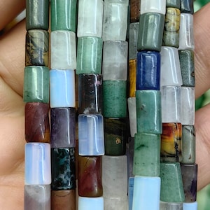 May include: A strand of colourful gemstone beads, featuring various shades of green, brown, blue, and white. The beads are rectangular in shape and have a polished finish.