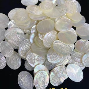 Peut inclure: Un tas de breloques en nacre de forme ovale blanche avec une image gravée de la Vierge Marie. Les breloques mesurent environ 15 x 20 mm.