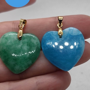 May include: Two heart-shaped pendants, one green and one blue, each with a gold-colored bail. The pendants are smooth and polished, with a glossy finish. The green pendant has a mottled appearance, while the blue pendant is a solid color.