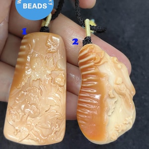 Pode incluir: Dois pingentes esculpidos com designs intrincados. Um apresenta um padrão floral, enquanto o outro tem uma forma orgânica texturizada. Ambos são de uma cor laranja-pêssego quente e são suspensos por cordões pretos. O texto "WK DIY Jewelry BEADS" está em um círculo azul.