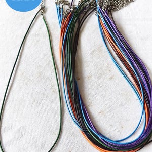 May include: A set of 18 colorful cord necklaces with silver clasps. The cords are in various colors, including green, blue, purple, orange, and black. The necklaces are all the same length and are perfect for making jewelry.