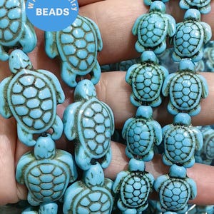 May include: A strand of turquoise blue turtle beads. The beads are strung on a clear elastic cord. The beads are approximately 2.5 cm in diameter and have a detailed turtle design. The beads are ideal for making jewellery or adding a touch of whimsy to any craft project.