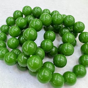 Pode incluir: Um fio de contas redondas de jade verde. As contas são lisas e polidas, e têm um leve brilho.