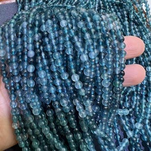 May include: A strand of blue and green gemstone beads. The beads are round and have a smooth, polished finish.