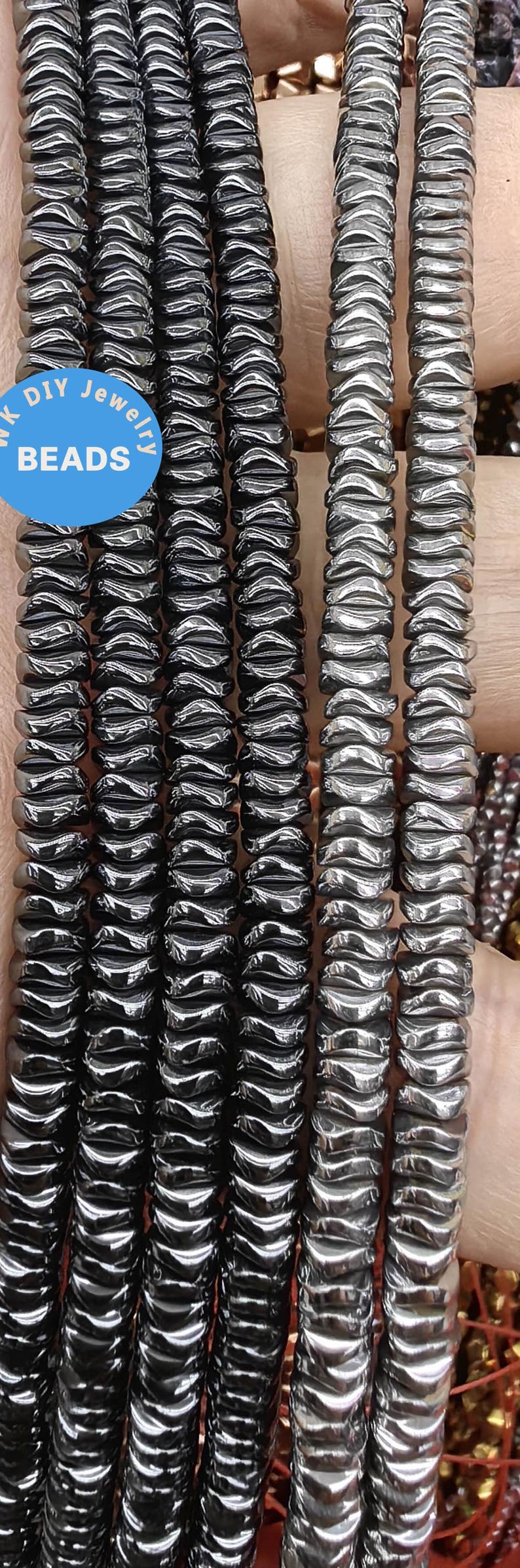 May include: A close-up of a strand of black hematite beads. The beads are faceted and have a shiny finish. The beads are arranged in a row and are being held by a hand. The text "DIY Jewelry Beads" is visible in the image.