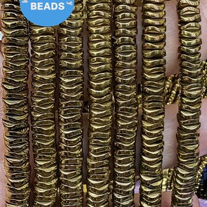 May include: A close-up of a strand of gold-toned hematite beads. The beads are faceted and have a wavy, irregular shape. The beads are strung on a clear elastic cord. The strand is approximately 18 inches long.  WK DIY Jewelry Beads.
