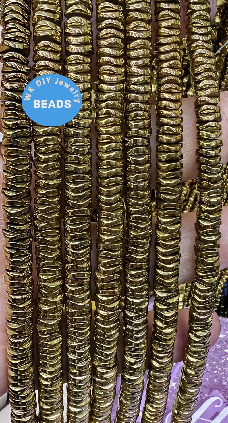 May include: A close-up of a strand of gold-toned hematite beads. The beads are faceted and have a wavy, irregular shape. The beads are strung on a clear elastic cord. The strand is approximately 18 inches long.  WK DIY Jewelry Beads.