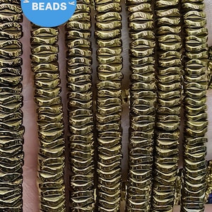 May include: A close-up of multiple strands of gold-toned hematite beads. The beads are faceted and have a wavy, textured surface. The beads are arranged in rows, creating a visual pattern.  WK DIY Jewelry Beads.