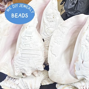 Peut inclure: Grandes coquilles de conque sculptées avec des motifs en relief complexes. Les coquilles sont principalement blanches avec un intérieur rose. Le texte "WK DIY JEWERLY BEADS" est dans un ovale bleu. Idéal pour la création de bijoux.
