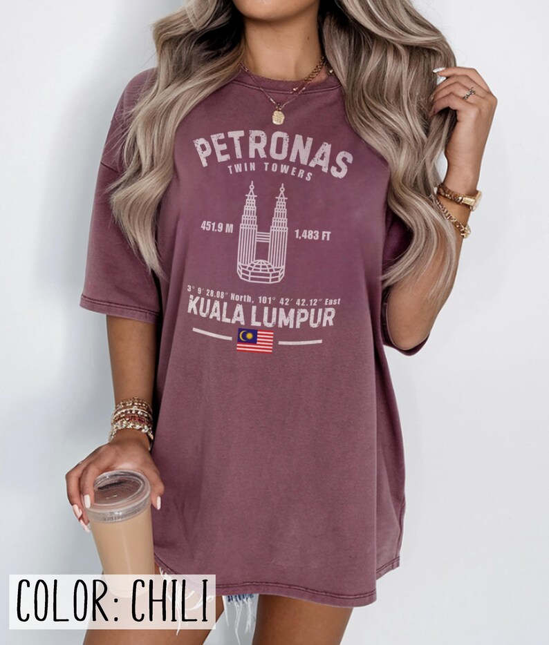 Peut inclure: Un t-shirt couleur chili avec un motif blanc des tours Petronas &agrave; Kuala Lumpur. L'impression comprend le texte Petronas Twin Towers, 451.9 M, 1 483 FT, des coordonn&eacute;es, Kuala Lumpur et un petit graphique du drapeau de la Malaisie.