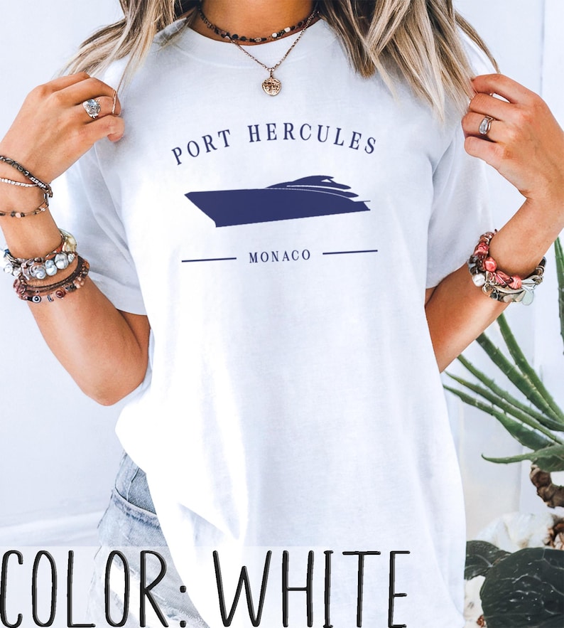 May include: White t-shirt with a navy blue graphic of a boat and the text "PORT HERCULES MONACO". The shirt is a crew neck style.