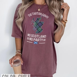 May include: A chili-colored short-sleeve t-shirt featuring a graphic of the map of Scotland filled with a green and blue tartan pattern. The text reads THE TARTAN ARMY, NO SCOTLAND NO PARTY, and includes a small blue and white Scottish flag icon.