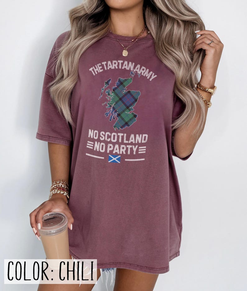 May include: A chili-colored short-sleeve t-shirt featuring a graphic of the map of Scotland filled with a green and blue tartan pattern. The text reads THE TARTAN ARMY, NO SCOTLAND NO PARTY, and includes a small blue and white Scottish flag icon.
