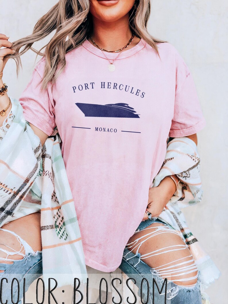 May include: A light pink t-shirt with the text "PORT HERCULES MONACO" and a navy blue boat graphic. The shirt is a soft, comfortable material.