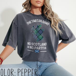 May include: A pepper-colored t-shirt featuring a distressed graphic of the map of Scotland filled with a green and blue tartan pattern. The text reads THE TARTAN ARMY, NO SCOTLAND NO PARTY, and includes a small blue and white Scottish flag icon.