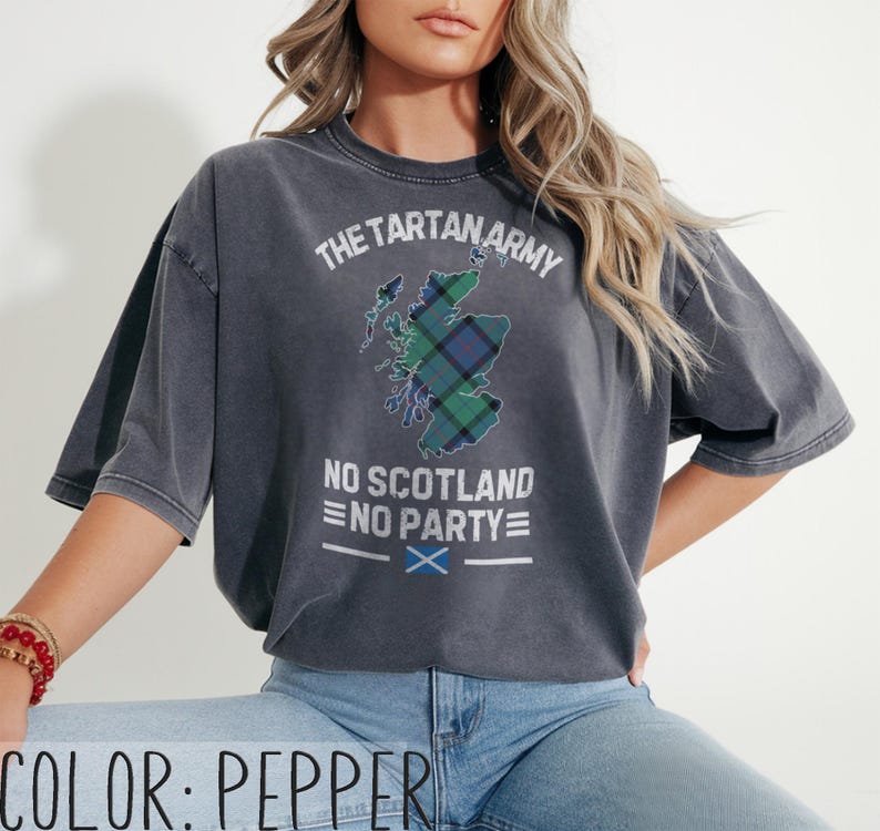 May include: A pepper-colored t-shirt featuring a distressed graphic of the map of Scotland filled with a green and blue tartan pattern. The text reads THE TARTAN ARMY, NO SCOTLAND NO PARTY, and includes a small blue and white Scottish flag icon.