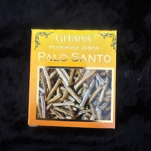 May include: A rectangular box with the words "GITANA PODEROSO JABÓN PALO SANTO" printed on the front. The box is yellow with gold trim and contains several pieces of Palo Santo wood.