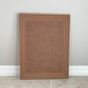 May include: A brown wood frame with multiple layers of molding. The frame is rectangular and has a smooth surface.