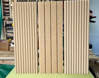May include: Three wooden panels with different styles of vertical grooves. The panels are light brown and have a smooth, slightly textured surface.
