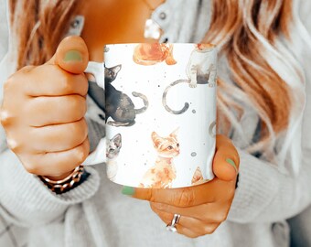 May include: White ceramic mug with a colorful watercolor pattern of cats. The cats are in various poses, including sitting, standing, and lying down. The mug has a black handle.