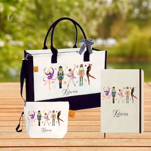 Puede incluir: Un conjunto de tres artículos: un bolso tote, un neceser y un cuaderno. Cada artículo presenta un fondo blanco con detalles y asas moradas. El diseño incluye ilustraciones de bailarinas y cascanueces, con el nombre "Katarina" debajo.