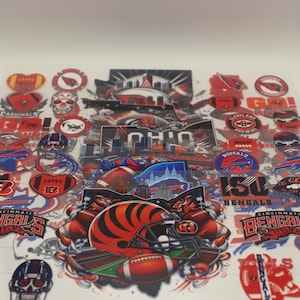May include: A collection of colorful stickers featuring various American football team logos and graphics. The stickers include team names, helmets, and other related imagery, with a focus on the Cincinnati Bengals and Ohio.