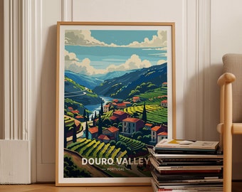 May include: Framed art print of the Douro Valley in Portugal. The landscape features a river winding through green hills with vineyards and red-roofed buildings. The sky is blue with white clouds. The print is in a light wood frame.