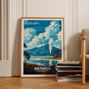 May include: A framed poster with a colorful illustration of a mountain with steam rising from the top, a lake, and trees. The poster has the text "Rotorua - New Zealand" at the bottom.
