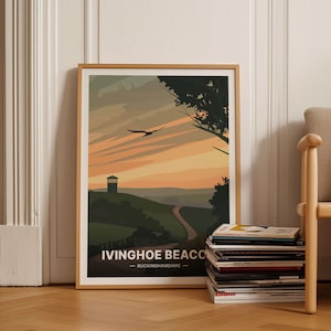 Puede incluir: Un póster enmarcado con una ilustración panorámica de una colina con una torre y un camino sinuoso. El cielo es una puesta de sol naranja y amarilla vibrante con un pájaro volando por encima. El texto en el póster dice "Ivinghoe Beacon - Buckinghamshire".