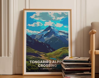 May include: A framed poster with a colorful illustration of a mountain range with a blue sky and white clouds. The text "Tongariro Alpin Crossing - New Zealand" is at the bottom of the poster.