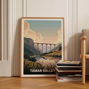 May include: A framed print of a landscape scene with a large stone arch bridge over a river. The print is titled "Tamar Valley".