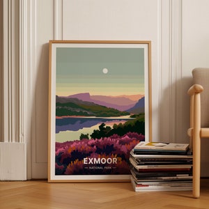 Könnte beinhalten: Ein gerahmter Druck einer Landschaftsszene mit einem See, Bergen und einem Vollmond am Himmel. Der Druck ist in einem hellen Holzrahmen und hat den Text "Exmoor - National Park" unten.