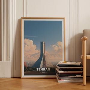 May include: A framed art print featuring a stylized illustration of the Azadi Tower in Tehran, Iran. The image displays the white concrete monument against a blue sky with soft clouds and distant mountains, with the text TEHRAN IRAN at the bottom.