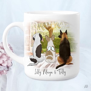 Puede incluir: Taza de cerámica blanca con un diseño de tres perros de dibujos animados mirando por una ventana una escena soleada al aire libre. Los perros son un perro blanco y negro, un perro marrón y blanco con alas de ángel y un perro negro y marrón. Los nombres "Lilly, Maya & Tilly" están escritos en la taza.